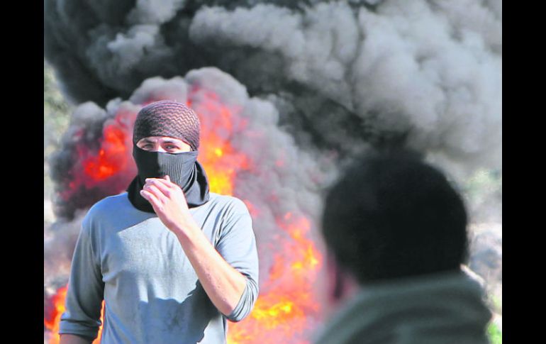 Palestinos queman neumáticos en una manifestación en contra de las expropiaciones de tierras por parte de Israel en Cisjordania. AFP  /