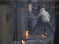 Manifestantes tratan de derribar las barricadas policiales. REUTERS  /