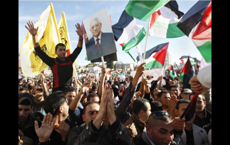 Palestinos ondean banderas nacionales y del presidente Abás, a su llegada a Ramala. AP  /