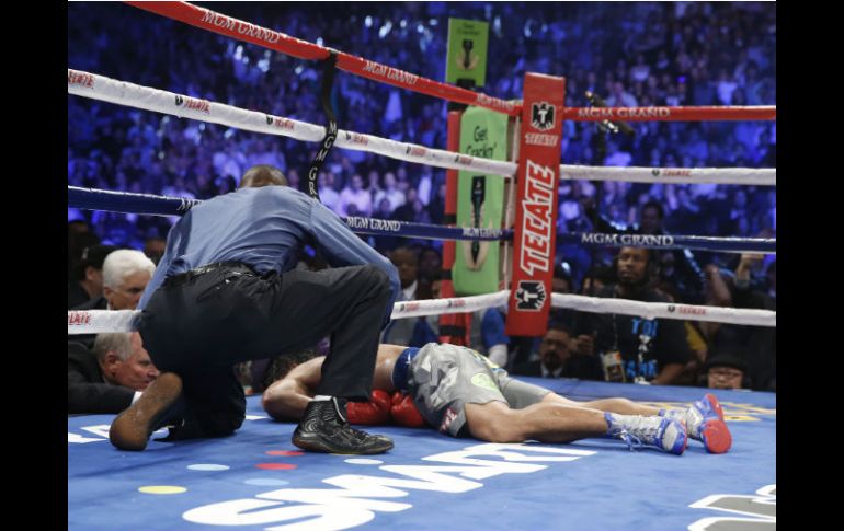 Pacquiao yace en el ring mientras el referi, Kenny Bayless, se arrodilla a su lado. AP  /