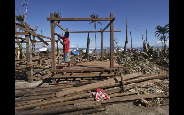 Un hombre filipino trata dereconstruir su casa, tras el paso del tifón. EFE  /