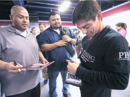 Complaciente. El púgil de Los Mochis, Jorge Arce, firma unos guantes a un aficionado. ESPECIAL  /