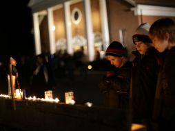 Tres niños observan las luces de veladoras encendidas afuera de un templo. REUTERS  /