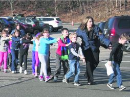 Procesión del miedo. Maestros de la escuela Sandy Hook conducen a varios niños hacia resguardo luego del tiroteo. AP  /