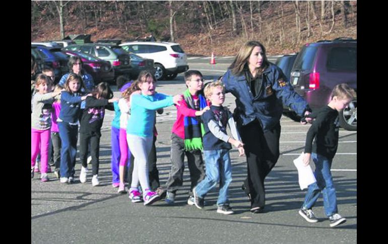 Procesión del miedo. Maestros de la escuela Sandy Hook conducen a varios niños hacia resguardo luego del tiroteo. AP  /