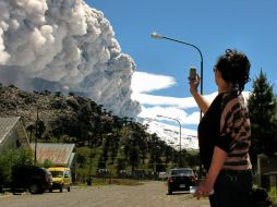 Mujer toma una foto con su celular del volcán Copahue arrojando cenizas en Caviahue, Provincia de Neuquén, Argentina. AFP  /