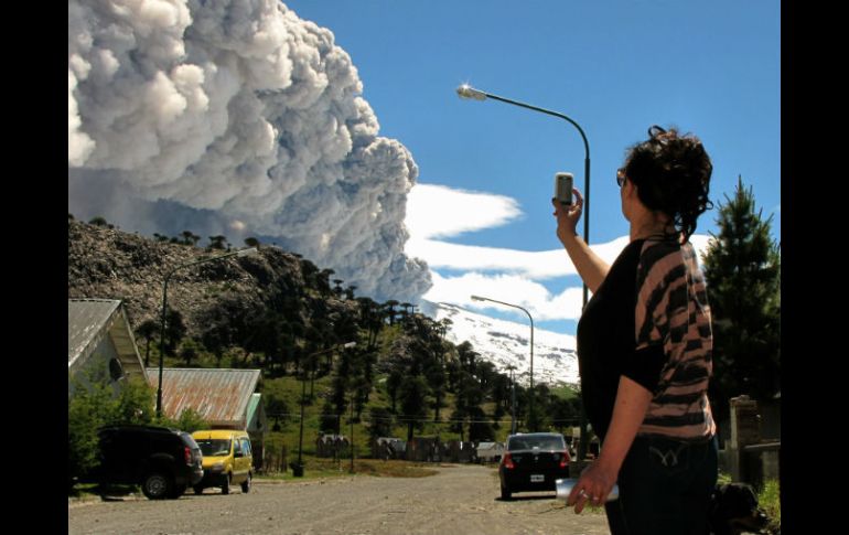 Mujer toma una foto con su celular del volcán Copahue arrojando cenizas en Caviahue, Provincia de Neuquén, Argentina. AFP  /