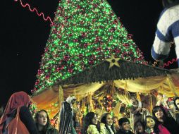 Palestinos posan junto a un árbol de Navidad en el Cuadrado del Pesebre, fuera de la Iglesia de la Natividad, en Belén. AP  /