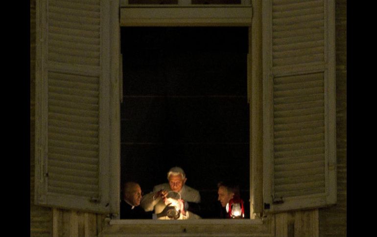 El Papa (c) enciende el Cirio de la Paz colocado en la ventana de su apartamento, que da a la plaza de San Pedro. EFE  /