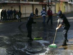 Gendarmes municipal limpian la sangre y el vidrio después de los enfrentamientos entre hombres armados y policías en Ayotlán. REUTERS  /