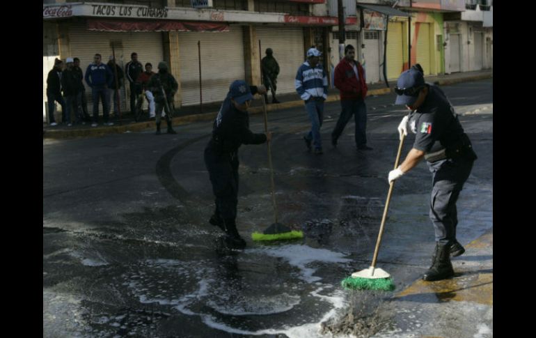 Gendarmes municipal limpian la sangre y el vidrio después de los enfrentamientos entre hombres armados y policías en Ayotlán. REUTERS  /