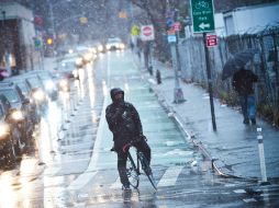 Un ciclista espera para cruzar la calle mientras una tormenta de nieve llega a Nueva York. AFP  /