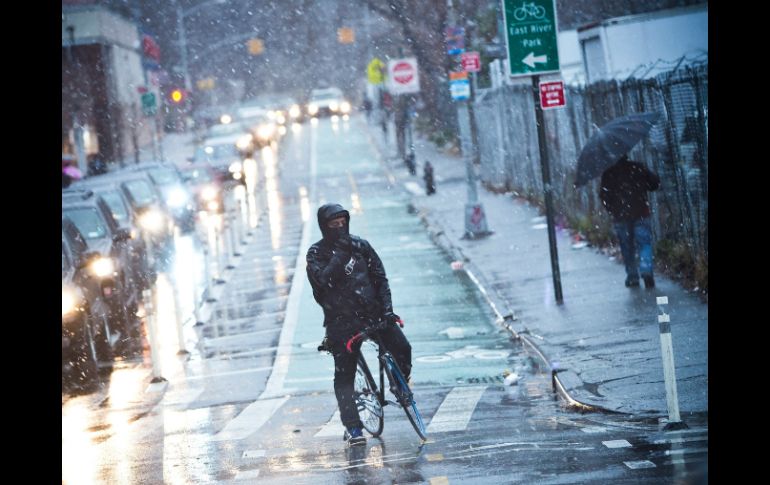 Un ciclista espera para cruzar la calle mientras una tormenta de nieve llega a Nueva York. AFP  /