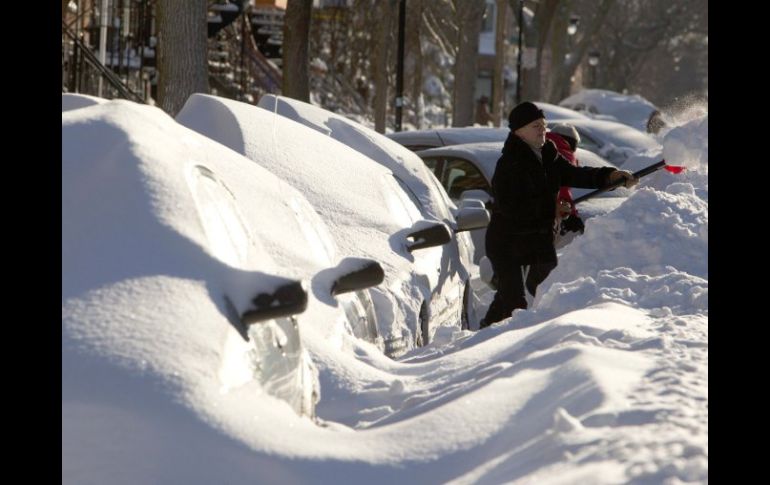 Dos vecinos se dan a la tarea de quitar la nieve de encima de sus automóviles hoy, tras la nevada en Montreal. REUTERS  /