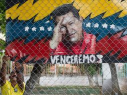 Un hombre coloca una manta con la imagen de Chávez. EFE EFE /