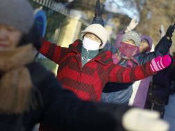 Varias personas, muy abrigadas, calienta para mantener la temperatura corporal debido a las bajas temperaturas registradas en China. EFE /