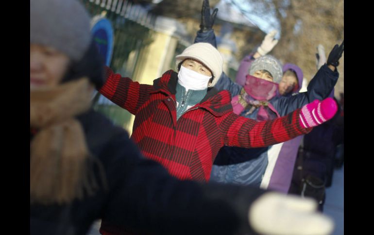 Varias personas, muy abrigadas, calienta para mantener la temperatura corporal debido a las bajas temperaturas registradas en China. EFE /