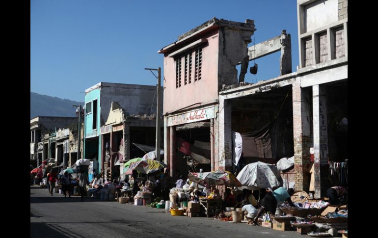 Personas caminan cerca de las ruinas de los locales comerciales de la avenida Desallines, en la capital haitiana. EFE /