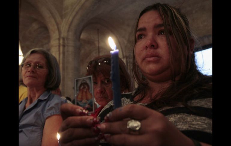 Una mujer sostiene una vela durante una misa en honor a Hugo Chávez REUTERS /