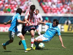 Sergio Pérez trata de pasar la marca de dos jugadores del San Luis en el partido.  /