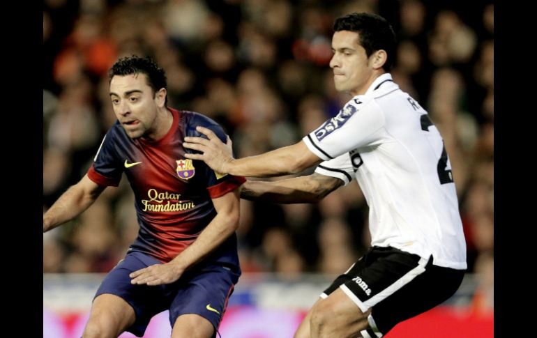 Xavi (izq.) sale lesionado del juego ante Valencia y tardará 15 días en recuperarse. EFE /