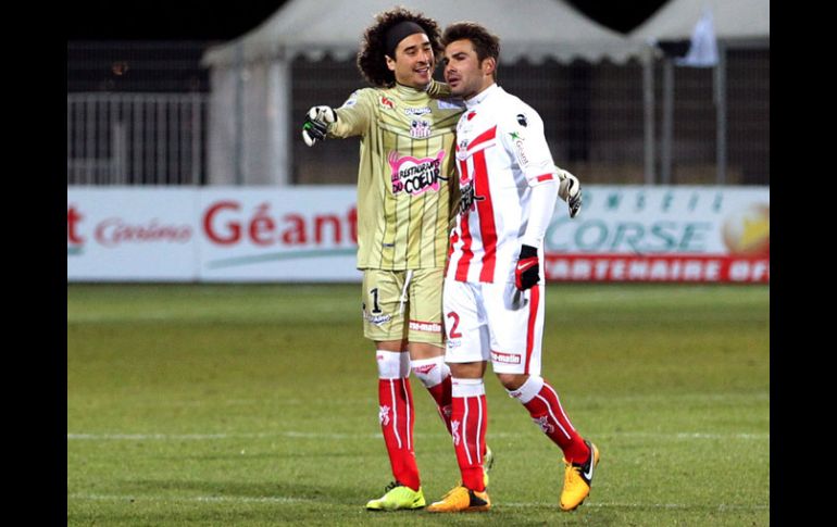 Guillermo Ochoa bromea con Adrián Mutu al terminar el partido. AFP /