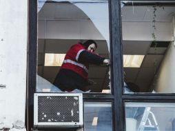 Un trabajador retira los cristales de las ventanas rotas por la ola expansiva creada por el impacto de un meteorito. EFE /