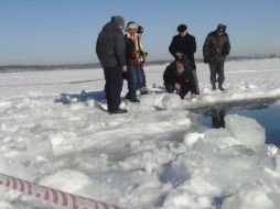 Autoridades obserban el agujero que dejó el meteorito al estrellarse en el lago de Chebarkul, cerca de Chelyabinsk, Rusia. EFE /