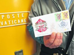 Recuerdo. Un hombre sostiene un sobre con la estampilla creada para usarse durante el periodo que consigna la Sede vacante. AFP /