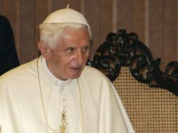 El papa emérito, que viste una gorra blanca y se protege del frío con un abrigo blanco mientras camina ayudado por un bastón. ARCHIVO /