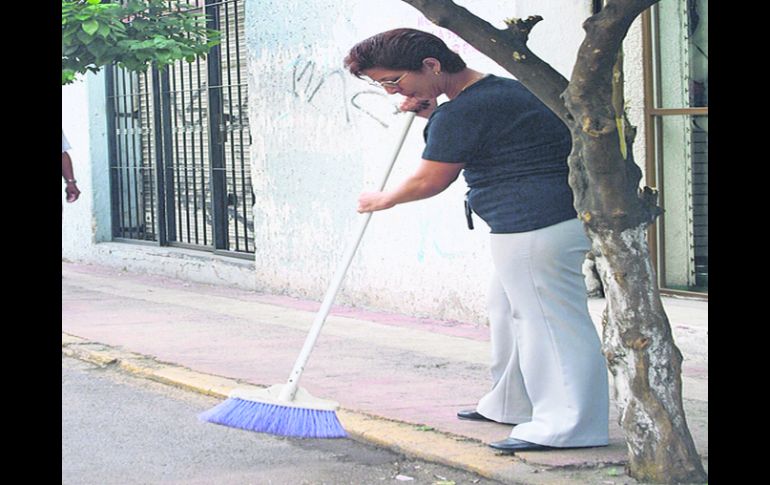 Manos a la escoba. Una vecina limpia una acera del primer cuadro de Guadalajara. EL INFORMADOR /