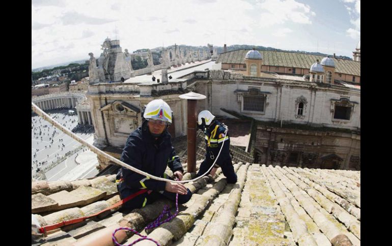 Últimos toques. Bomberos de El Vaticano realizan reparaciones menores en la chimenea de la Capilla Sixtina, previo al Cónclave. AFP /