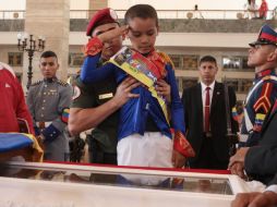 Un niño vestido de Simón Bolívar, saluda a restos de Chávez en su ataúd. EFE /