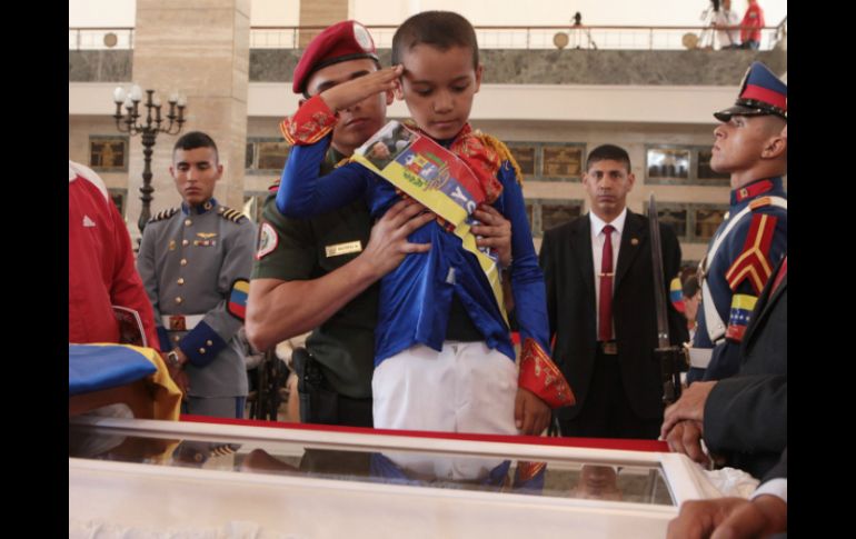 Un niño vestido de Simón Bolívar, saluda a restos de Chávez en su ataúd. EFE /