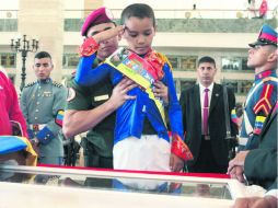 Un niño vestido de Simón Bolivar hace un saludo militar delante del féretro del comandante Hugo Chávez. AFP /