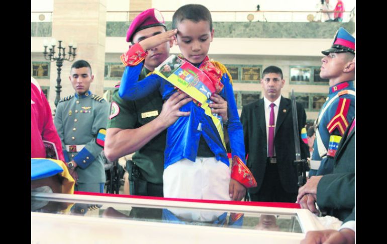 Un niño vestido de Simón Bolivar hace un saludo militar delante del féretro del comandante Hugo Chávez. AFP /