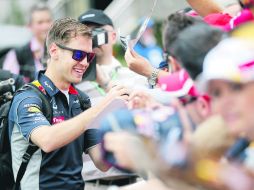 Aclamado. Sebastian Vettel reparte autógrafos a su llegada al Circuito del Albert Park. AP /