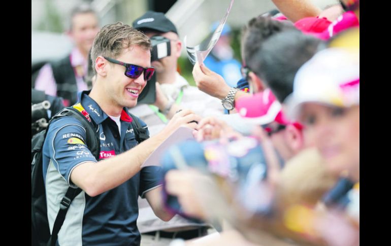 Aclamado. Sebastian Vettel reparte autógrafos a su llegada al Circuito del Albert Park. AP /