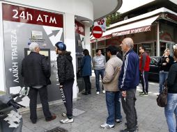 Un grupo de personas hace cola junto al cajero automático de una sucursal cerrada del banco Laiki. EFE /