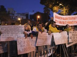 Varios asistentes muestran pancartas durante una manifestación frente al Parlamento de Chipre. EFE /