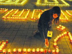 Una joven tunecina prende veladoras en la plaza principal que quedó oscura por 60 minutos. AFP /