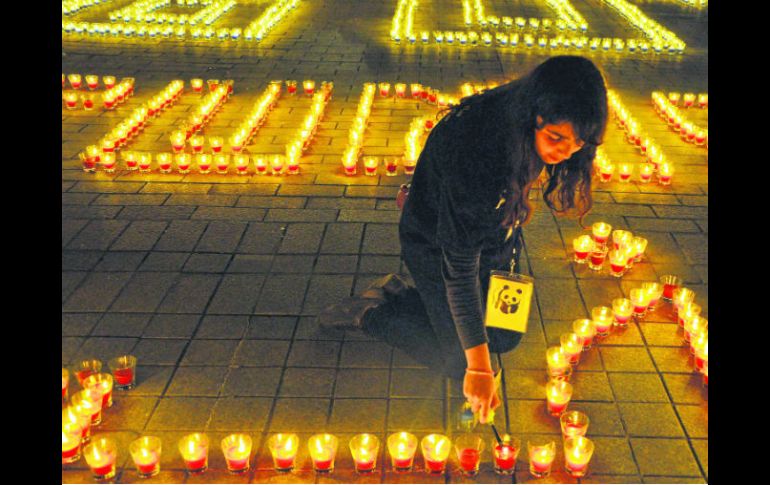 Una joven tunecina prende veladoras en la plaza principal que quedó oscura por 60 minutos. AFP /