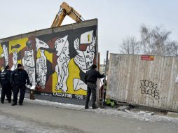 Policías vigilan mientras una máquina excavadora trabaja en la construcción, al lado de una sección del antiguo Muro de Berlín. EFE /