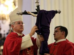 El cardenal Francisco Robles cubre con una tela morada la imagen de Cristo crucificado.  /