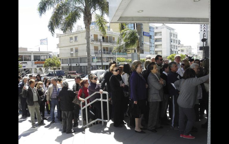 Varias personas hacen cola a las puertas de una sucursal del Banco Laiki en Nicosia. EFE /