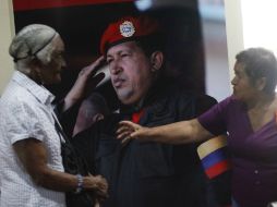 Dos mujeres charlan frente a una fotografía de Chávez. EFE /