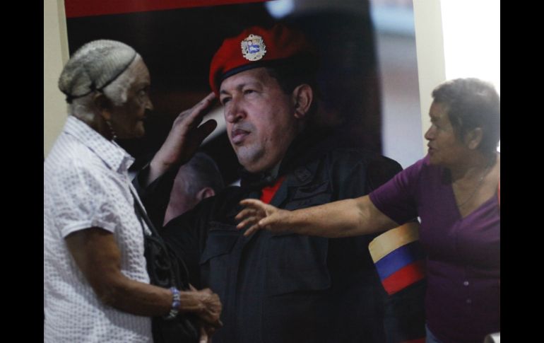 Dos mujeres charlan frente a una fotografía de Chávez. EFE /