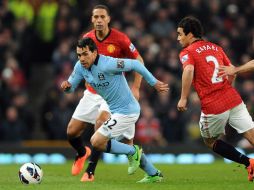 El jugador del Manchester City Carlos Tévez conduce el balón ante la marca de Rafael Da Silva (d), del ManU. EFE /