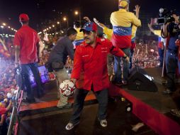 Diego Armando Maradona firma balones y los patea hacia los chavistas. AP /