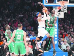 Imparable. Carmelo Anthony (blanco) recibe una falta de Kevin Garnett (derecha) en su intento por anotar. EFE /